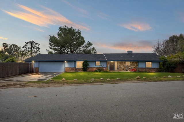 ranch-style house featuring brick siding, fence, a garage, driveway, and a front lawn