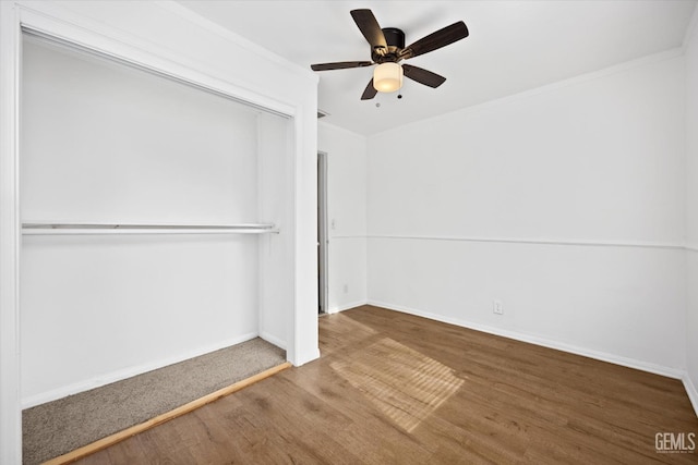 unfurnished bedroom with hardwood / wood-style flooring, ceiling fan, crown molding, and a closet