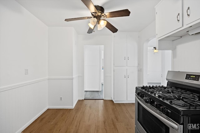 kitchen featuring light wood-type flooring, white cabinetry, stainless steel range with gas cooktop, and ceiling fan