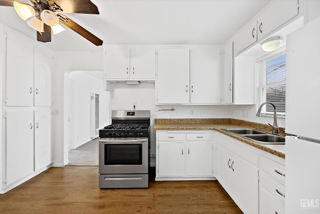 kitchen with stainless steel gas stove, white refrigerator, white cabinetry, and sink