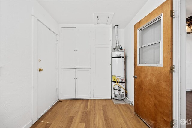 corridor featuring light hardwood / wood-style floors and strapped water heater