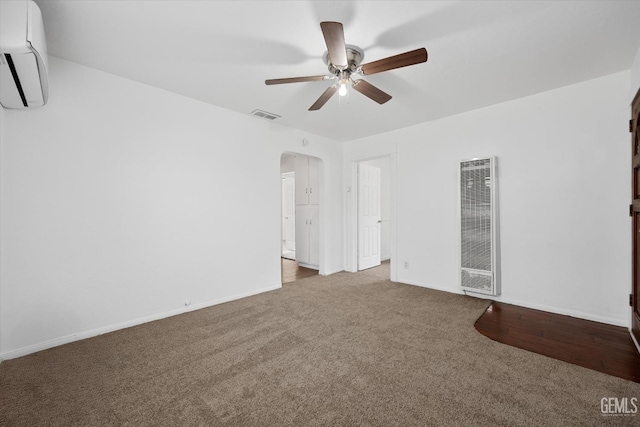 empty room with ceiling fan, light colored carpet, and a wall mounted air conditioner