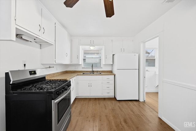 kitchen featuring white fridge, white cabinetry, and stainless steel gas range