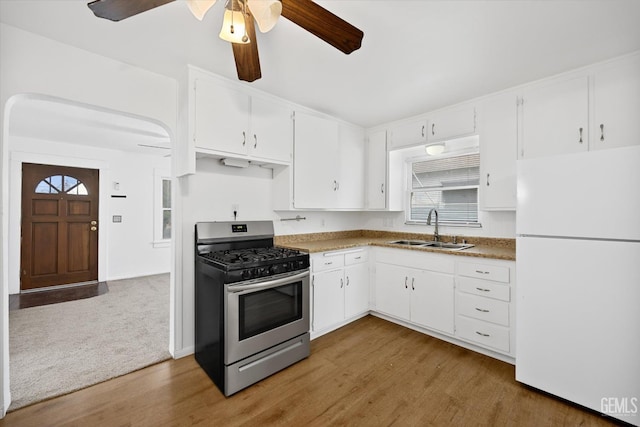 kitchen with gas range, white cabinetry, sink, and white fridge