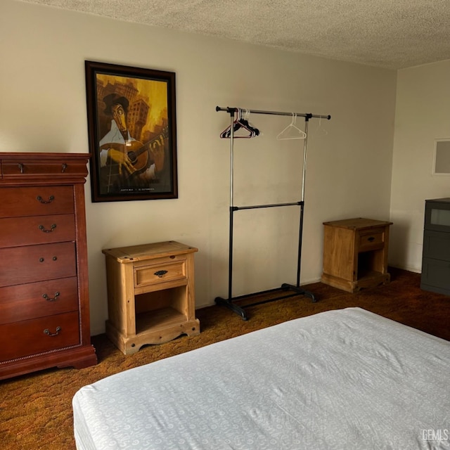 bedroom with dark colored carpet and a textured ceiling