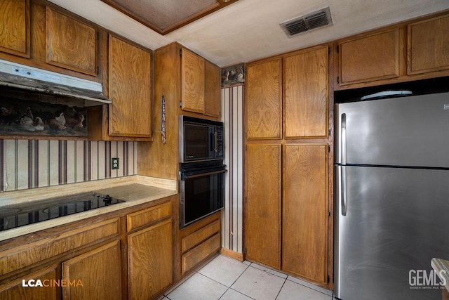 11705 Cactus Dr, Bakersfield, CA 93312 - kitchen with black appliances, brown cabinetry, light tile patterned flooring, light countertops, and under cabinet range hood