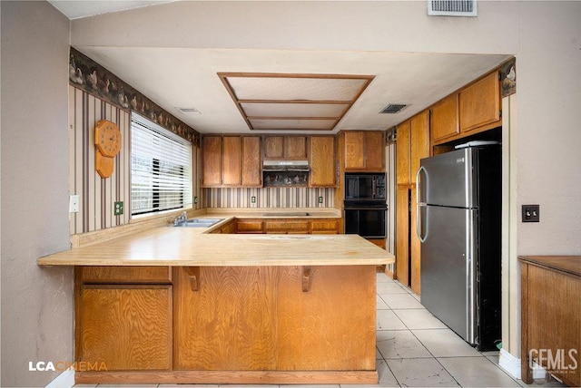 11705 Cactus Dr, Bakersfield, CA 93312 - kitchen with black appliances, a sink, light countertops, and brown cabinets