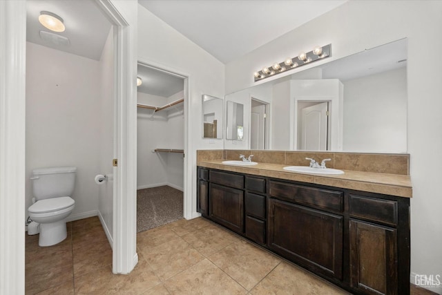 bathroom with tile patterned flooring, a sink, a spacious closet, and toilet