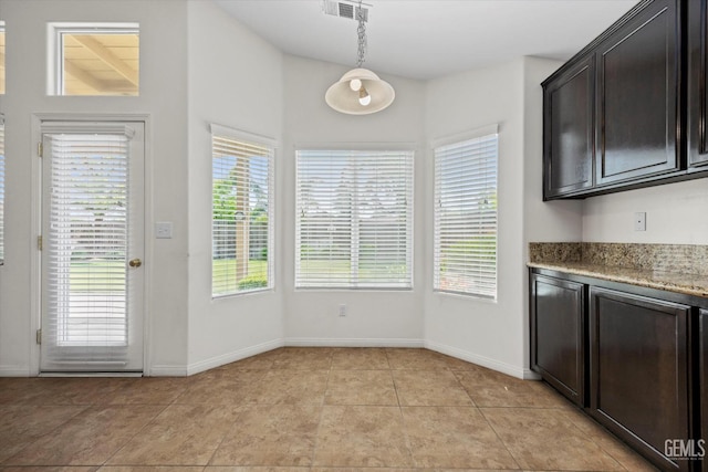 kitchen with visible vents, pendant lighting, baseboards, light stone counters, and light tile patterned floors