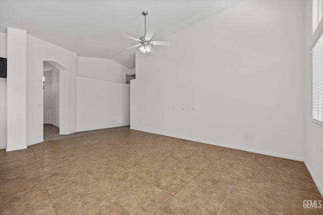spare room featuring arched walkways, a ceiling fan, light tile patterned floors, and vaulted ceiling