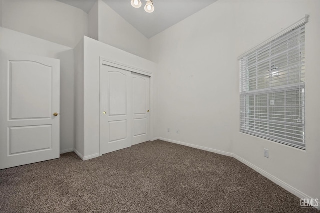 unfurnished bedroom featuring carpet floors, baseboards, high vaulted ceiling, and a closet