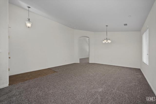 carpeted empty room featuring an inviting chandelier, arched walkways, baseboards, and visible vents