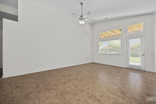 tiled empty room featuring baseboards, a ceiling fan, high vaulted ceiling, and visible vents