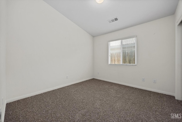 carpeted empty room with baseboards, visible vents, and vaulted ceiling