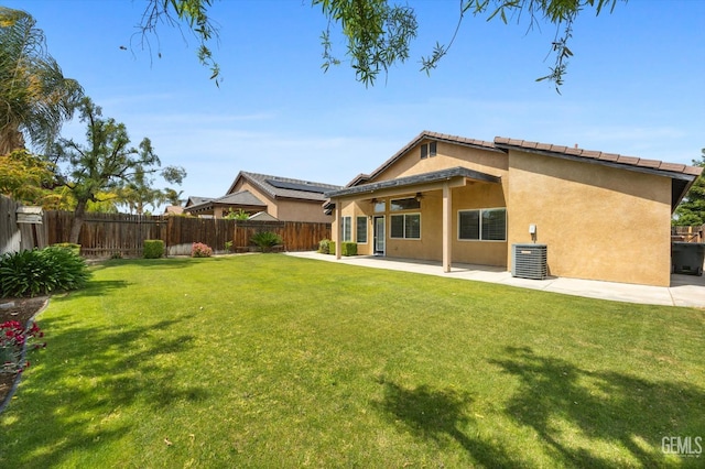 rear view of property featuring stucco siding, ceiling fan, a fenced backyard, a lawn, and a patio