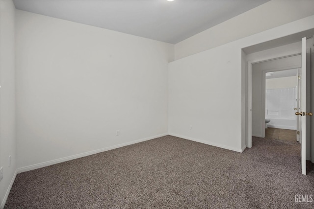 unfurnished room featuring dark carpet and baseboards