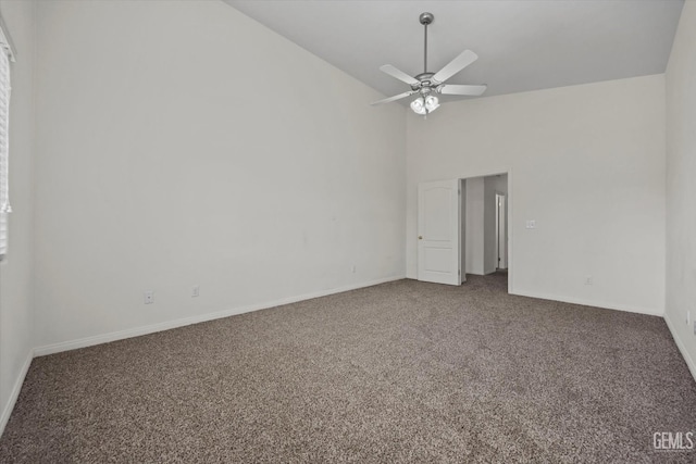 carpeted empty room featuring ceiling fan, baseboards, and high vaulted ceiling