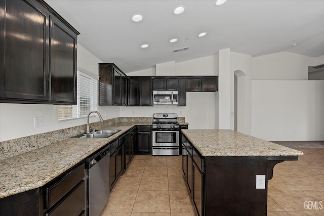 kitchen featuring visible vents, appliances with stainless steel finishes, a center island, vaulted ceiling, and a sink