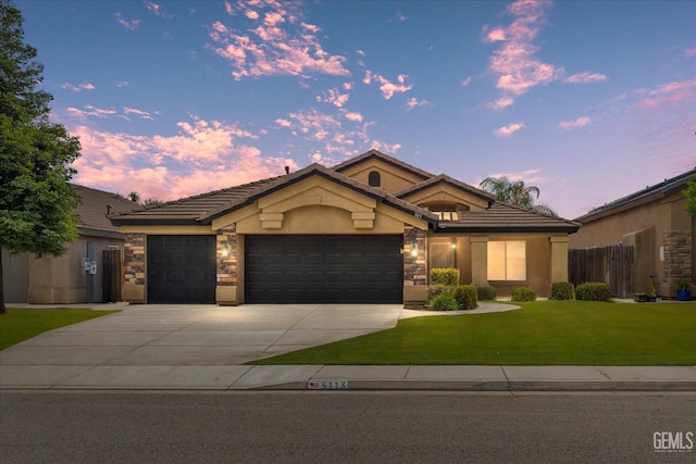 view of front of house featuring an attached garage, stone siding, stucco siding, a front yard, and a tiled roof