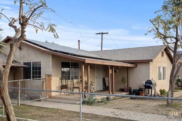 ranch-style home with solar panels and a patio area