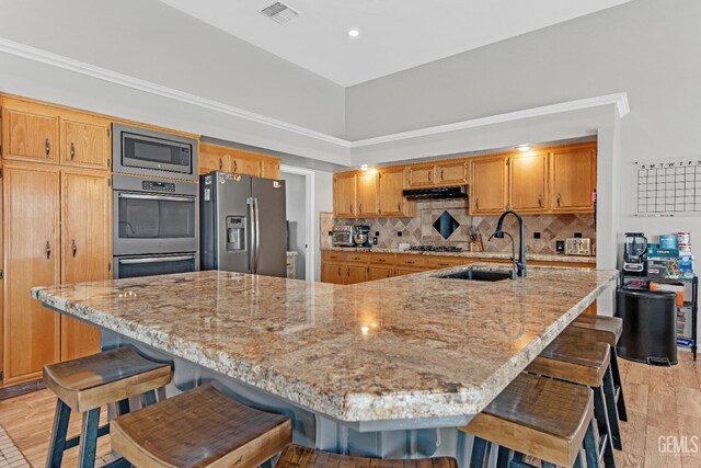 11520 Pinehaven Ave, Bakersfield, CA 93312 - kitchen with appliances with stainless steel finishes, under cabinet range hood, a sink, decorative backsplash, and light wood-type flooring