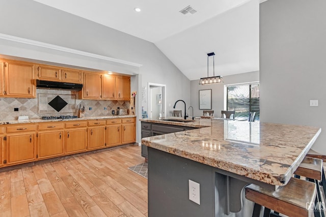 11520 Pinehaven Ave, Bakersfield, CA 93312 - kitchen with a sink, light wood-type flooring, under cabinet range hood, a kitchen bar, and decorative backsplash
