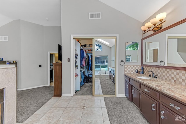 11520 Pinehaven Ave, Bakersfield, CA 93312 - bathroom with vanity, decorative backsplash, a walk in closet, tile patterned flooring, and high vaulted ceiling