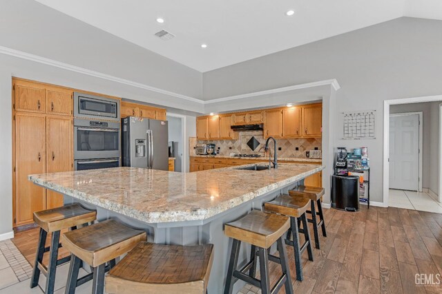 11520 Pinehaven Ave, Bakersfield, CA 93312 - kitchen featuring appliances with stainless steel finishes, under cabinet range hood, light wood finished floors, decorative backsplash, and recessed lighting