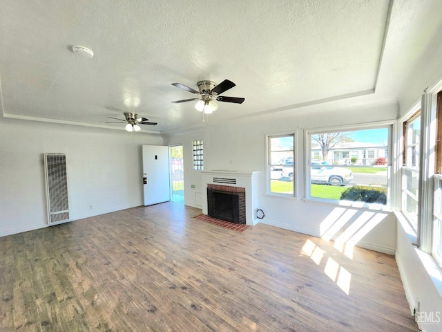 209 Bedford Way, Bakersfield, CA 93308 - unfurnished living room featuring wood finished floors, baseboards, ceiling fan, a textured ceiling, and a brick fireplace