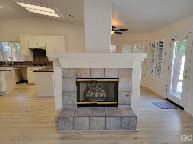 room details featuring sink, decorative backsplash, hardwood / wood-style flooring, a tiled fireplace, and ceiling fan