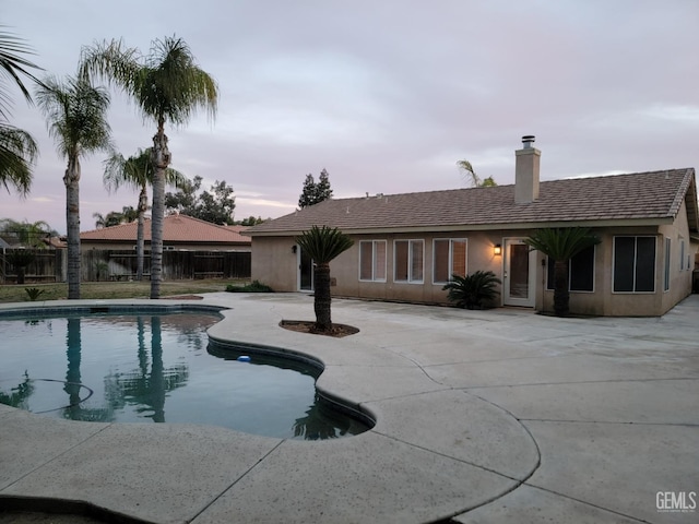 pool at dusk with a patio area