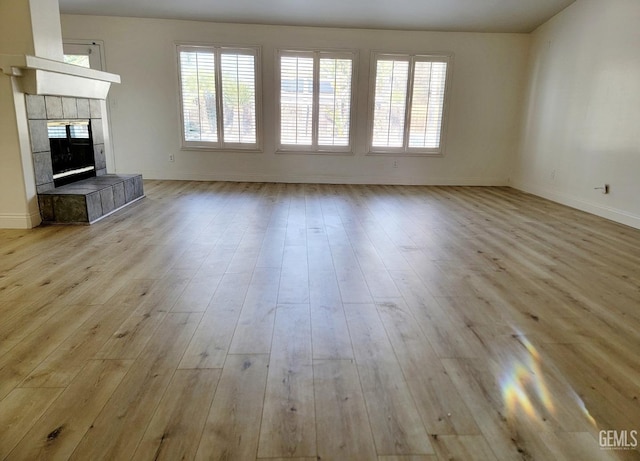 unfurnished living room featuring a tile fireplace and light wood-type flooring