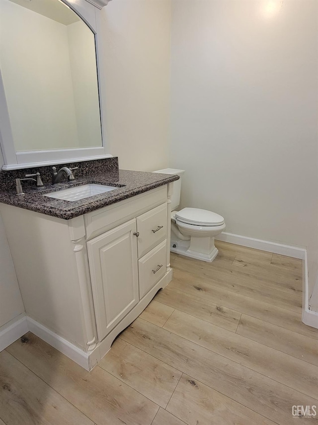 bathroom featuring wood-type flooring, vanity, and toilet