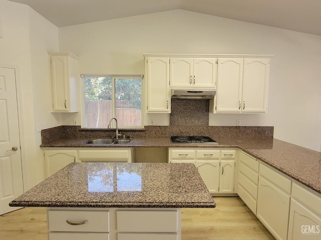 kitchen with sink, dark stone countertops, and light wood-type flooring