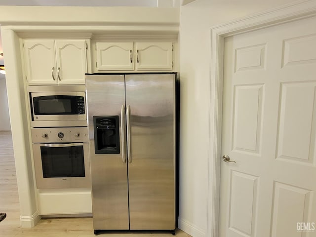 kitchen with white cabinets, stainless steel appliances, and light wood-type flooring