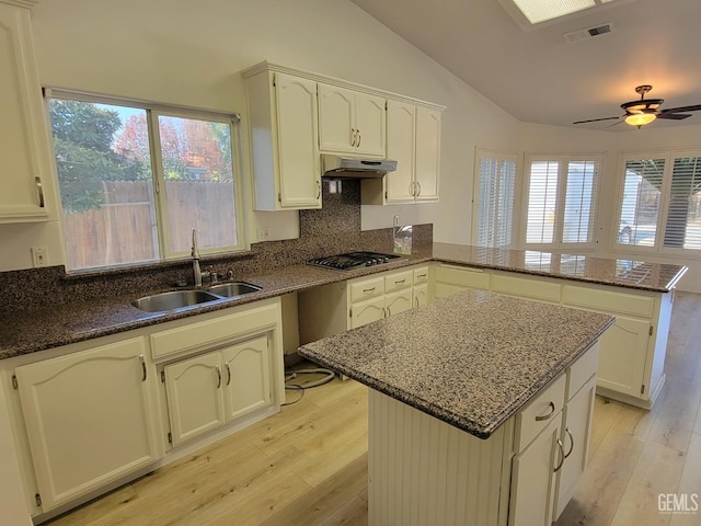 kitchen featuring stainless steel gas cooktop, a center island, kitchen peninsula, and sink