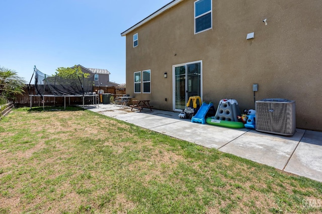 5906 Commonwealth Ave, Bakersfield, CA 93313 - back of house featuring a trampoline, a patio, a fenced backyard, and stucco siding