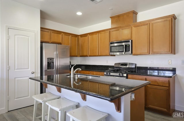 5812 Turquoise Ridge Dr, Bakersfield, CA 93313 - kitchen with stainless steel appliances, a breakfast bar area, dark stone countertops, an island with sink, and brown cabinets