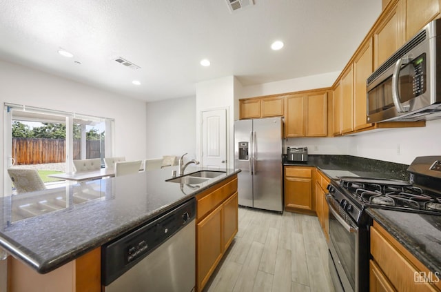 5812 Turquoise Ridge Dr, Bakersfield, CA 93313 - kitchen featuring appliances with stainless steel finishes, light wood-style floors, a center island with sink, dark stone countertops, and recessed lighting