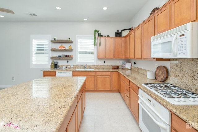 kitchen featuring light stone countertops, white appliances, and sink