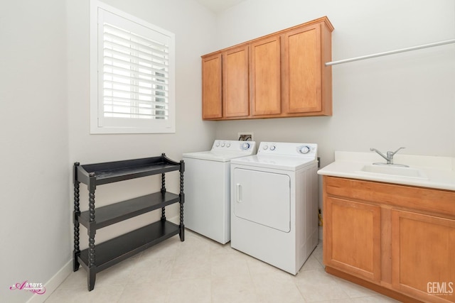 clothes washing area featuring washing machine and dryer, sink, and cabinets