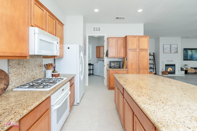 kitchen featuring light stone countertops, washer and dryer, and white appliances