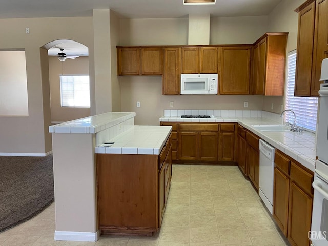 11016 Snowcreek Falls Ave, Bakersfield, CA 93312 - kitchen with white appliances, tile countertops, brown cabinets, a ceiling fan, and arched walkways