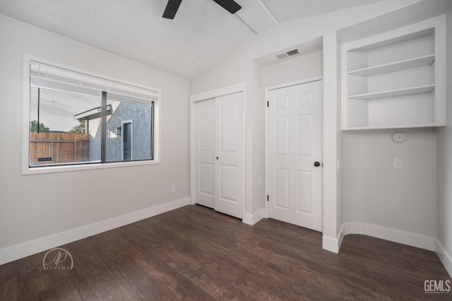 unfurnished bedroom featuring vaulted ceiling, ceiling fan, dark wood-type flooring, a textured ceiling, and a closet