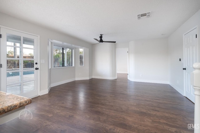 unfurnished living room featuring dark wood-type flooring, a textured ceiling, and ceiling fan