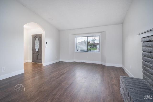 empty room featuring dark hardwood / wood-style flooring, vaulted ceiling, and a textured ceiling