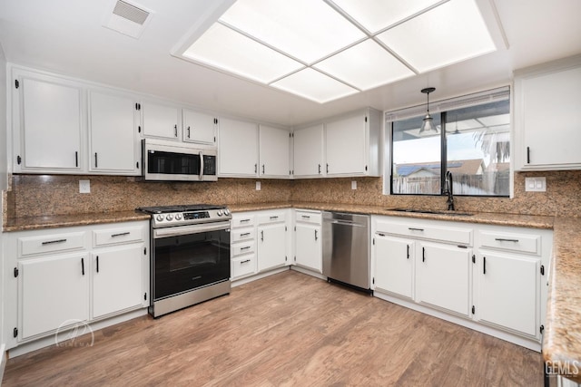 kitchen with hanging light fixtures, white cabinetry, appliances with stainless steel finishes, and sink