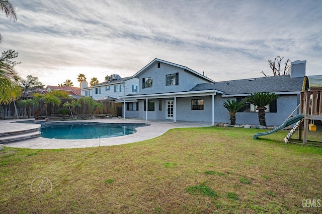 rear view of house featuring a fenced in pool, a lawn, a patio, and a playground