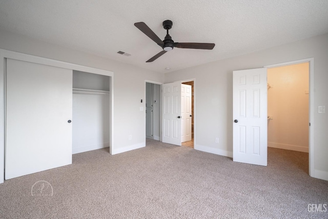 unfurnished bedroom featuring ceiling fan, light carpet, a closet, and a textured ceiling