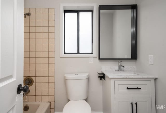 full bathroom featuring tiled shower / bath, vanity, and toilet